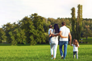 Family of wife, husband, and two children walking in grass